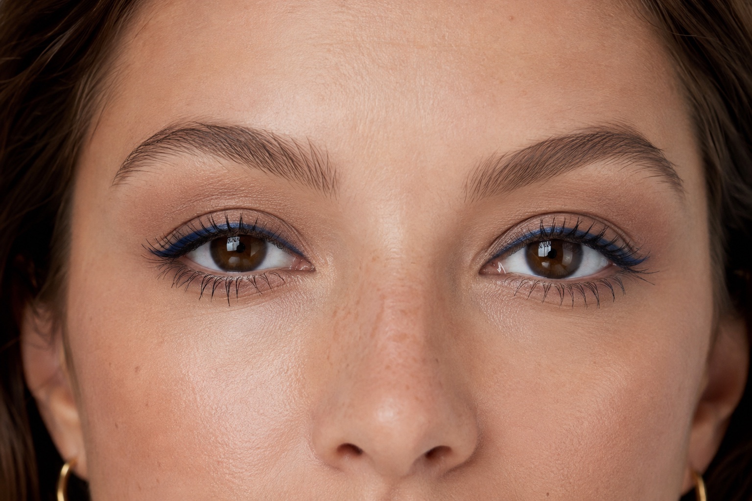 Brune øjne med tynd koboltblå eyeliner tæt mellem de øvre vipper